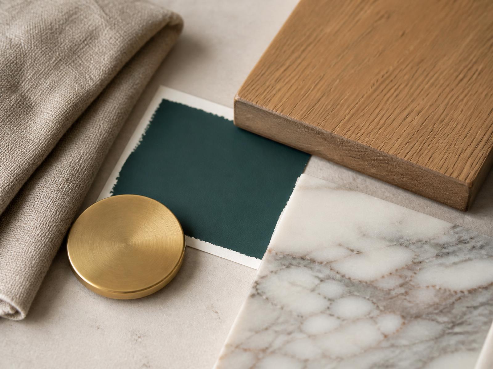 Oak, marble, brass and deep teal paint samples arranged on stone